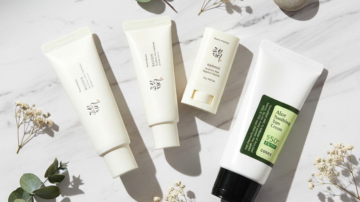 Lightweight Korean sunscreen tubes arranged on a clean marble surface with cica leaves